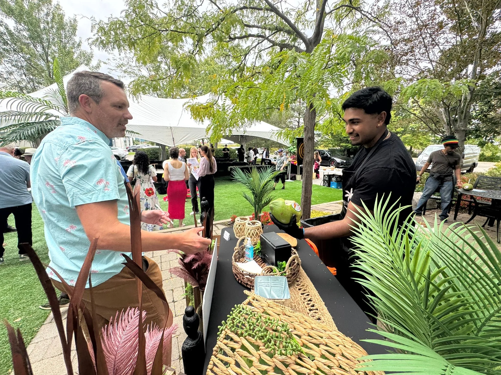 Andrew handing a freshly cut coconut to a guest at a corporate event